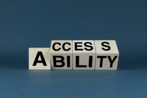 Wooden blocks arrange to spell “Accessibility” with the word “Access” partially stacked above on a blue background. 