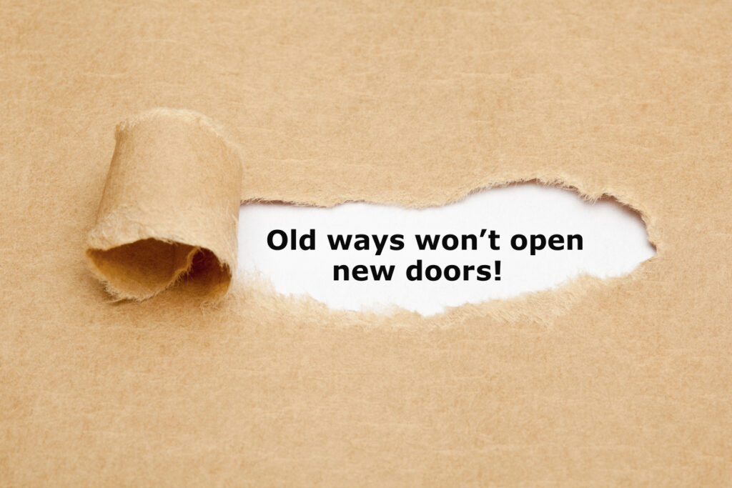 A torn brown paper with a hole in it revealing the quote “Old ways won’t open new doors!”.